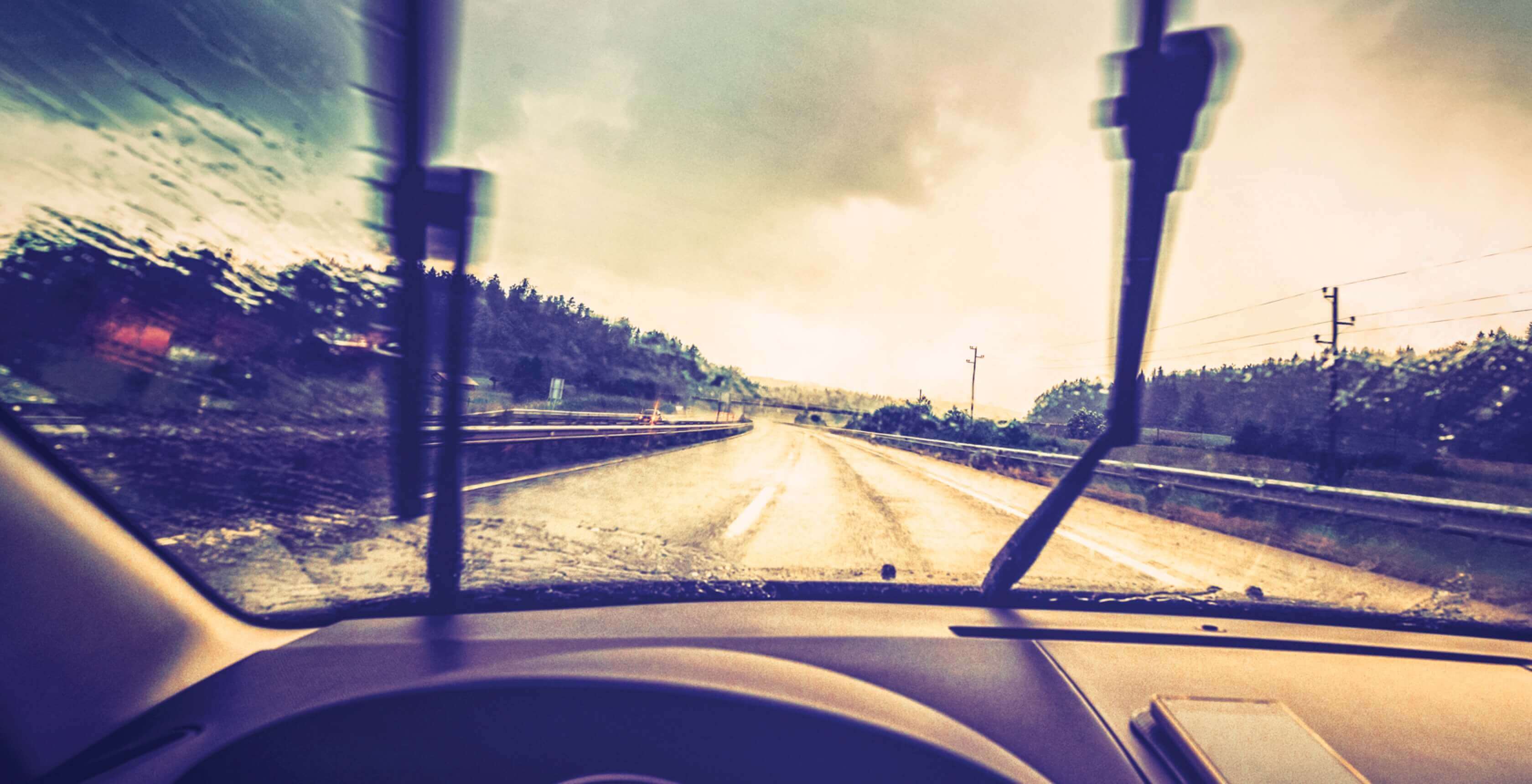 An image of a rain soaked windshield seen from the perspective of the driver